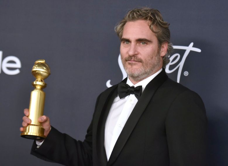Joaquin Phoenix memegang piala Golden Globe yang baru didapatkannya.